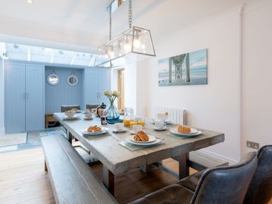 A dining room with a wooden table set for breakfast with croissants and juice at Whitsunday House in Carbis Bay