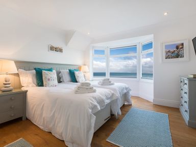 A bedroom with two single beds near a bay window with ocean view at Whitsunday House in Carbis Bay