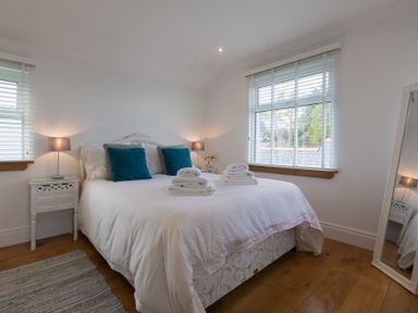 A bedroom with a bed and two bedside tables with lamps at Whitsunday House in Carbis Bay