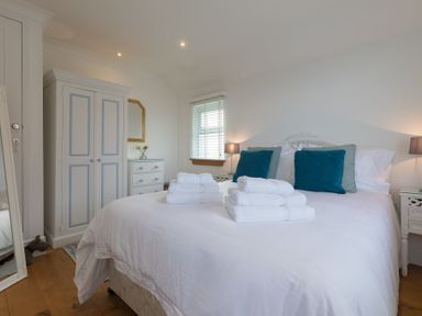 A bedroom with a double bed with white bedding and blue pillows in Whitsunday House Carbis Bay