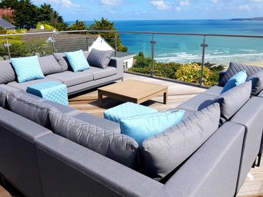 An outdoor seating area with gray sofas and blue cushions overlooking the ocean at Whitsunday House in Carbis Bay