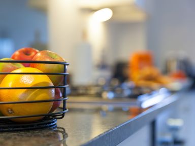 A kitchen counter with a fruit basket containing an orange and apples at Sea Mist in Carbis Bay