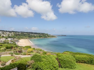 A coastal view with a sandy beach greenery and houses in the distance at Sea Mist in Carbis Bay