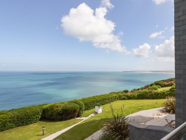 A coastal view with green lawn and bushes overlooking the sea at Sea Mist in Carbis Bay