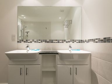 A bathroom with two sinks under a large mirror and tiled walls at Sea Mist in Carbis Bay