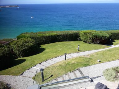 A garden with grass and hedges overlooking the ocean at Sea Mist in Carbis Bay