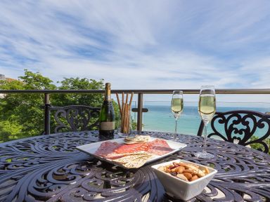 A table on a balcony with wine glasses bottle charcuterie and nuts overlooking the sea at Abalone in St Ives