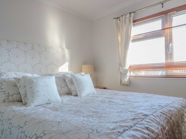 A bedroom with a bed with patterned bedding and pillows next to a window with curtains at Oak Lodge in Glasshouse