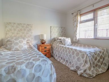 A bedroom with two single beds a wooden nightstand and a window at Oak Lodge in Glasshouse
