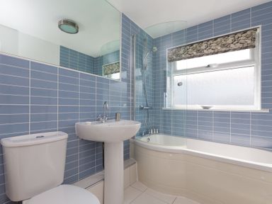 A bathroom with a toilet sink and bathtub with a shower at Atlantic Blue in Carbis Bay