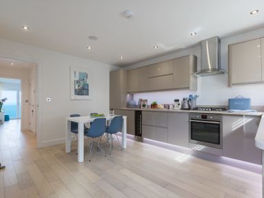 A kitchen with a dining table and chairs next to cabinets and an oven at Atlantic Watch 8 in Carbis Bay