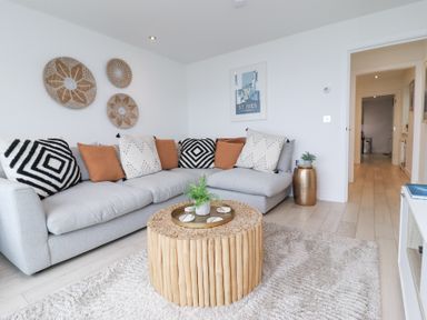A living room with a gray sectional sofa and a round wooden coffee table at Atlantic Watch 8 in Carbis Bay