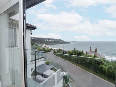 A balcony overlooking a road and coastline with houses and the sea beyond at Atlantic Watch 8 in Carbis Bay