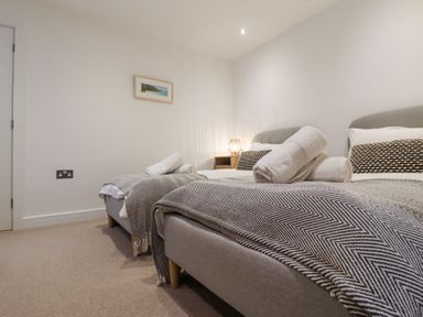 A bedroom with two single beds with rolled towels on each bed and a small lamp on a nightstand at Atlantic Watch 8 in Carbis Bay