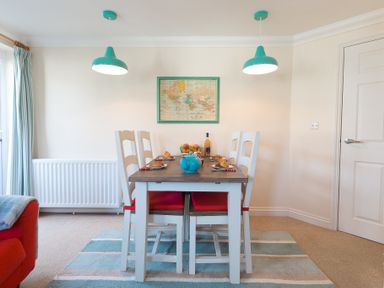 A dining table with four chairs under two pendant lights with a world map on the wall at Brinyloft in Carbis Bay