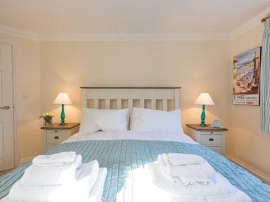 A bedroom with a double bed two bedside tables lamps and a blue bed cover at Brinyloft in Carbis Bay