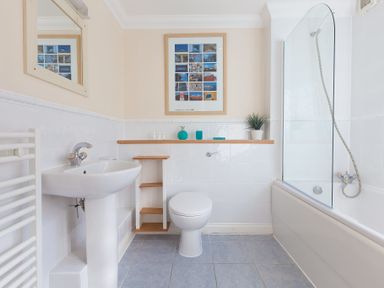 A bathroom with a pedestal sink toilet bathtub glass shower screen and framed pictures at Brinyloft in Carbis Bay