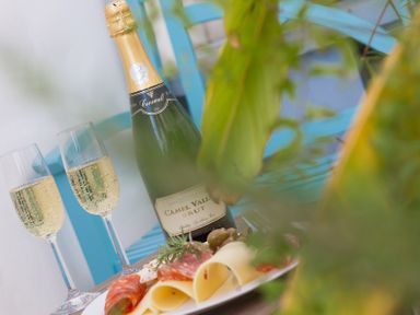A bottle of sparkling wine with two filled glasses and a plate of sliced cheese and meat on a table at Brinyloft in Carbis Bay