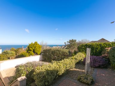 A garden with shrubs and a rotary clothesline with a view of the sea and houses in Carbis Bay