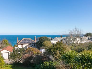 A view of houses with solar panels and trees overlooking the sea at Cornerways in Carbis Bay