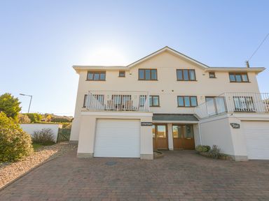 A two story house with a driveway garage and a balcony at Cornerways in Carbis Bay