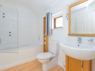 A bathroom with a bathtub shower toilet sink mirror and small window at Cornerways in Carbis Bay