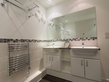 A bathroom with two sinks a large mirror a towel rack and wall decorations at Elanora in Carbis Bay