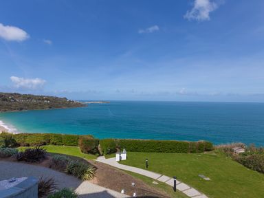 A coastal view with a grassy garden area and shrubs overlooking the ocean at Elanora in Carbis Bay
