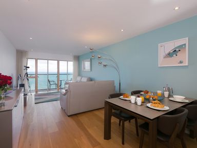 A living room with dining table set for breakfast and ocean view at Elanora in Carbis Bay