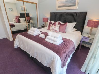 A bedroom with a bed with folded towels on a purple throw at Elanora in Carbis Bay