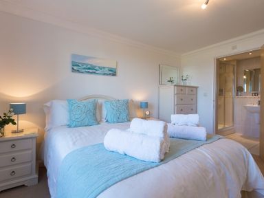 A bedroom with a bed towels on the bed and an ensuite bathroom at Gennaker in Carbis Bay