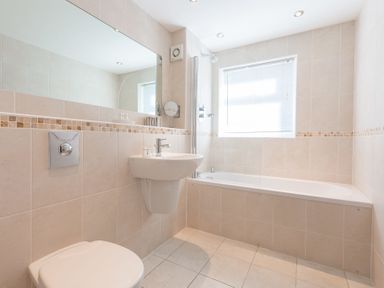A bathroom with a toilet sink bathtub mirror and window at Gennaker in Carbis Bay