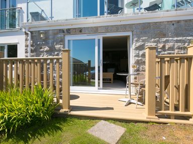 An outdoor deck with a small table and two chairs outside a sliding glass door at Gennaker in Carbis Bay