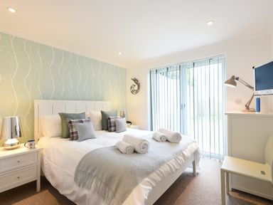 A bedroom with a double bed bedside tables lamps pillows and a throw at Halcyon Cove in Carbis Bay