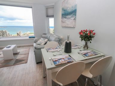 A living room with a table and sofa and view of the sea at Island View in Carbis Bay