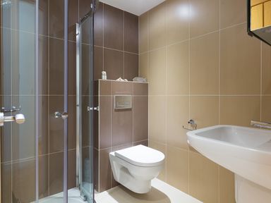A bathroom with a glass shower enclosure a wall-mounted toilet and a white sink at Kernow's Dream in Carbis Bay
