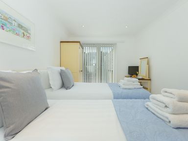 A bedroom with two single beds and folded towels on the beds at Kernow's Dream in Carbis Bay