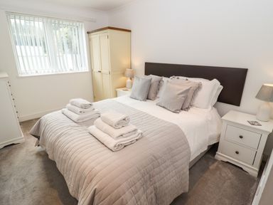 A bedroom with a bed with folded towels on it bedside tables with lamps a wardrobe and a chest of drawers at Kernow's Dream in Carbis Bay