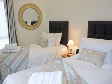 A bedroom with two single beds with striped and seashell patterned bedding at Ocean Cove in Carbis Bay