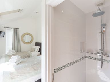 A bedroom with two single beds next to a bathroom with a shower at Ocean Cove in Carbis Bay