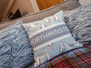 A close up of decorative pillows on a gray sofa with a patterned blanket at The View in St Ives