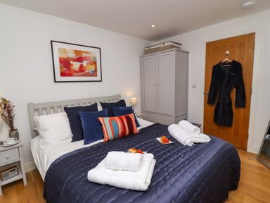 A bedroom with a bed covered in a dark blue quilt and white towels on top at The View in St Ives