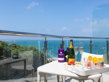 A balcony table with drinks and snacks overlooking the sea with glass and metal railing at Portside in Carbis Bay