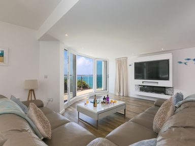A living room with leather sofas a coffee table and a large window overlooking the sea at Portside in Carbis Bay