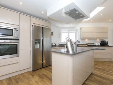 A kitchen with stainless steel appliances and white cabinets at Portside in Carbis Bay
