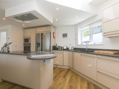 A kitchen with beige cabinets stainless steel appliances a window and wooden floor at Portside Carbis Bay