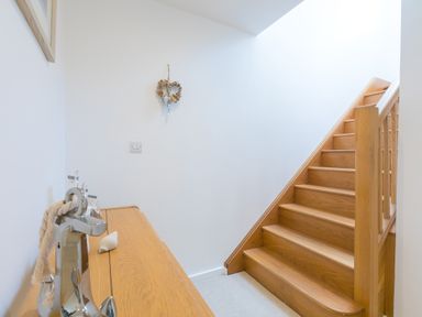 A wooden staircase next to a wooden cabinet with a decorative anchor and a wall hanging at Portside in Carbis Bay