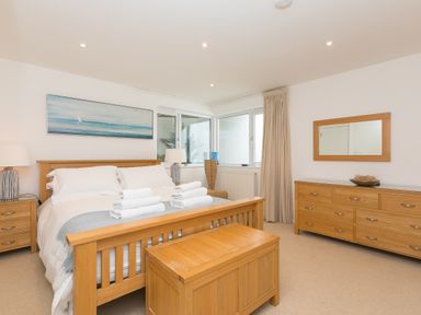 A bedroom with a wooden bed frame dresser and chest at Portside in Carbis Bay