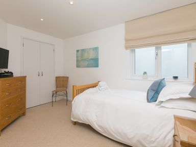 A bedroom with a single bed a wooden chest of drawers a chair and a window at Portside in Carbis Bay