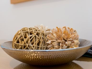 Decorative wooden balls in a hammered metal bowl on a wooden surface at Portside in Carbis Bay